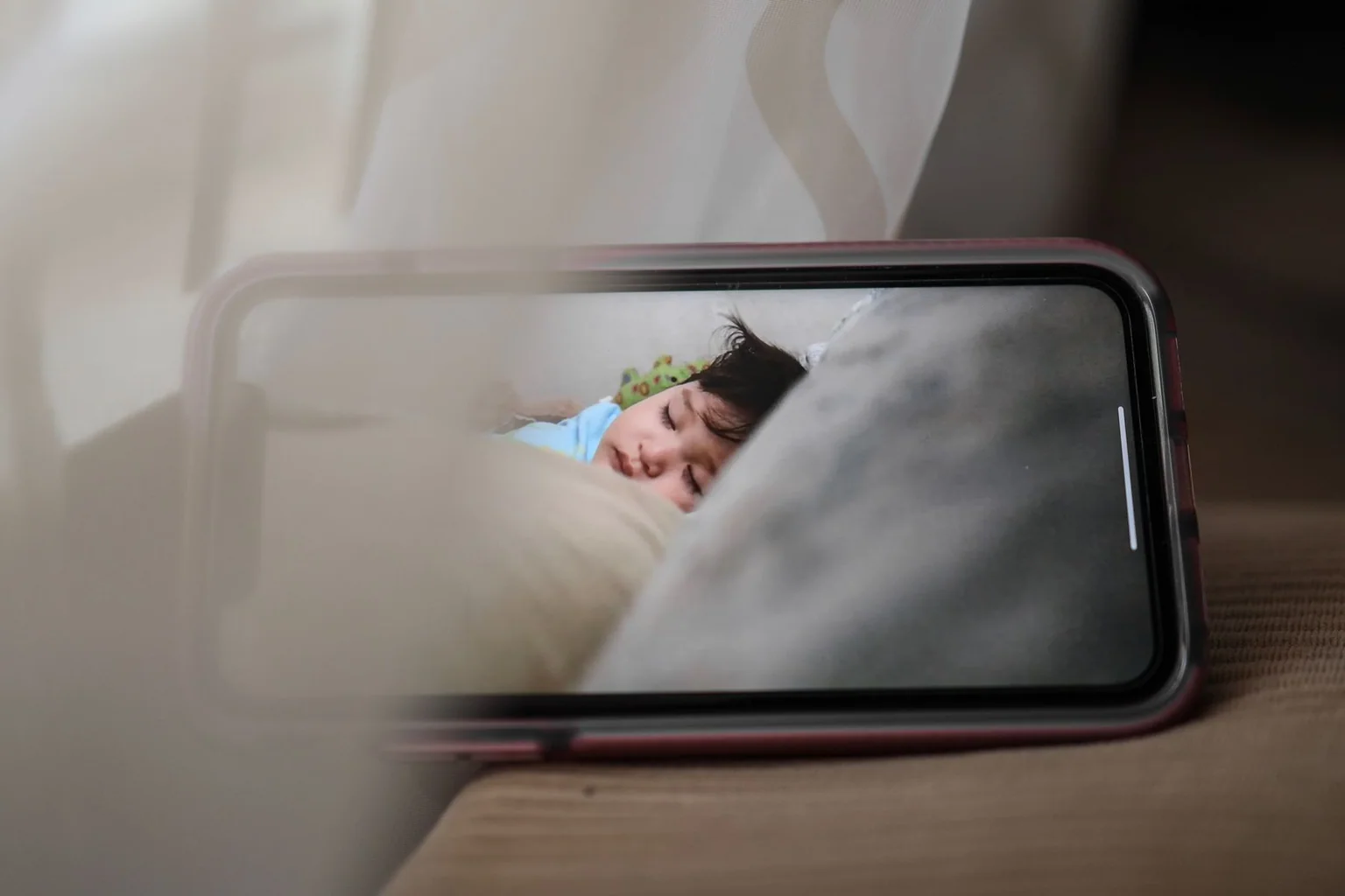 Smartphone displaying a sleeping baby on a monitor feed