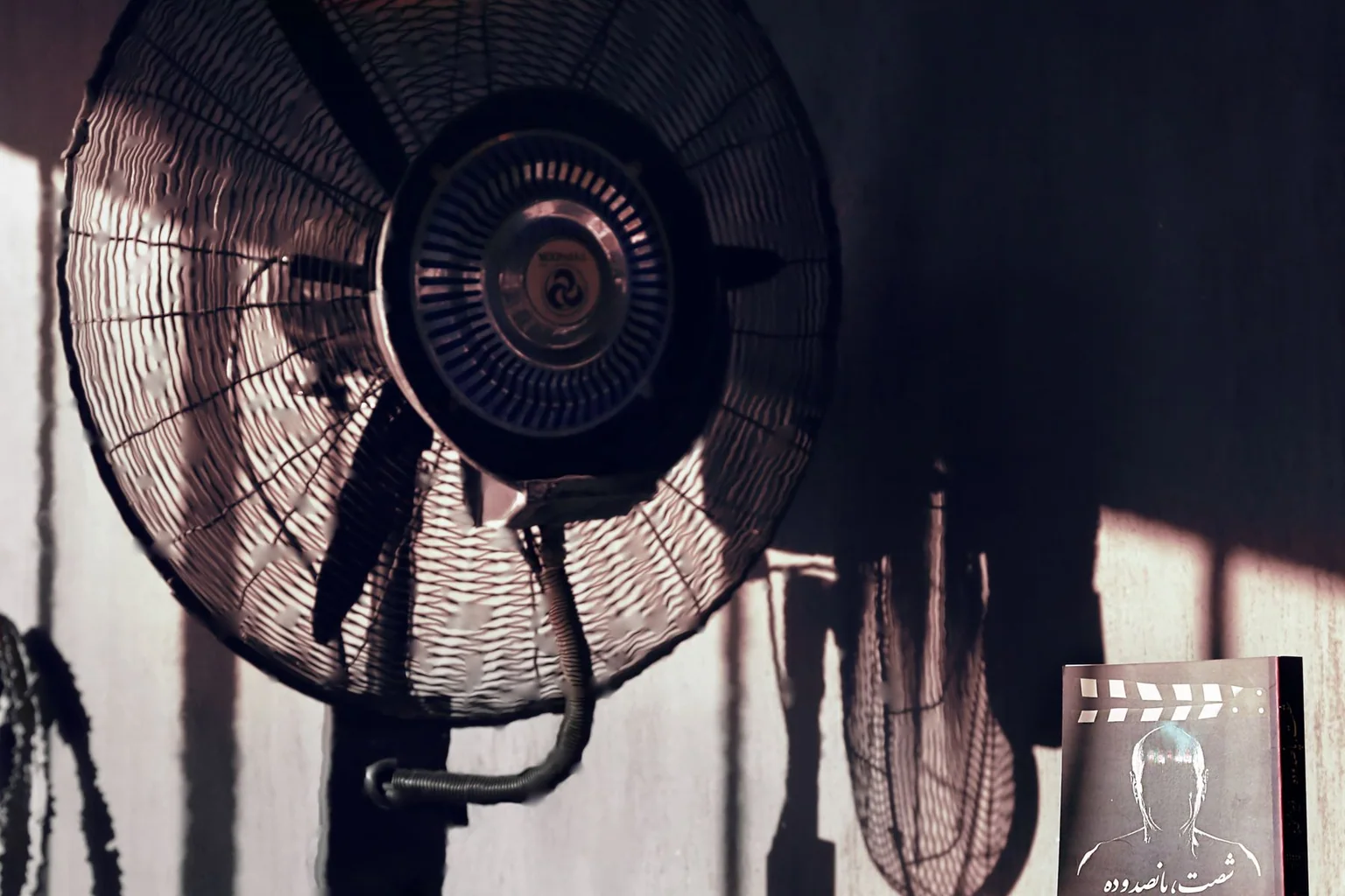 Large black electric fan positioned beside a wall in a room