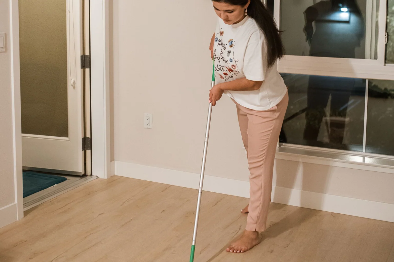 Person using a mop to clean a light-colored hard floor indoors