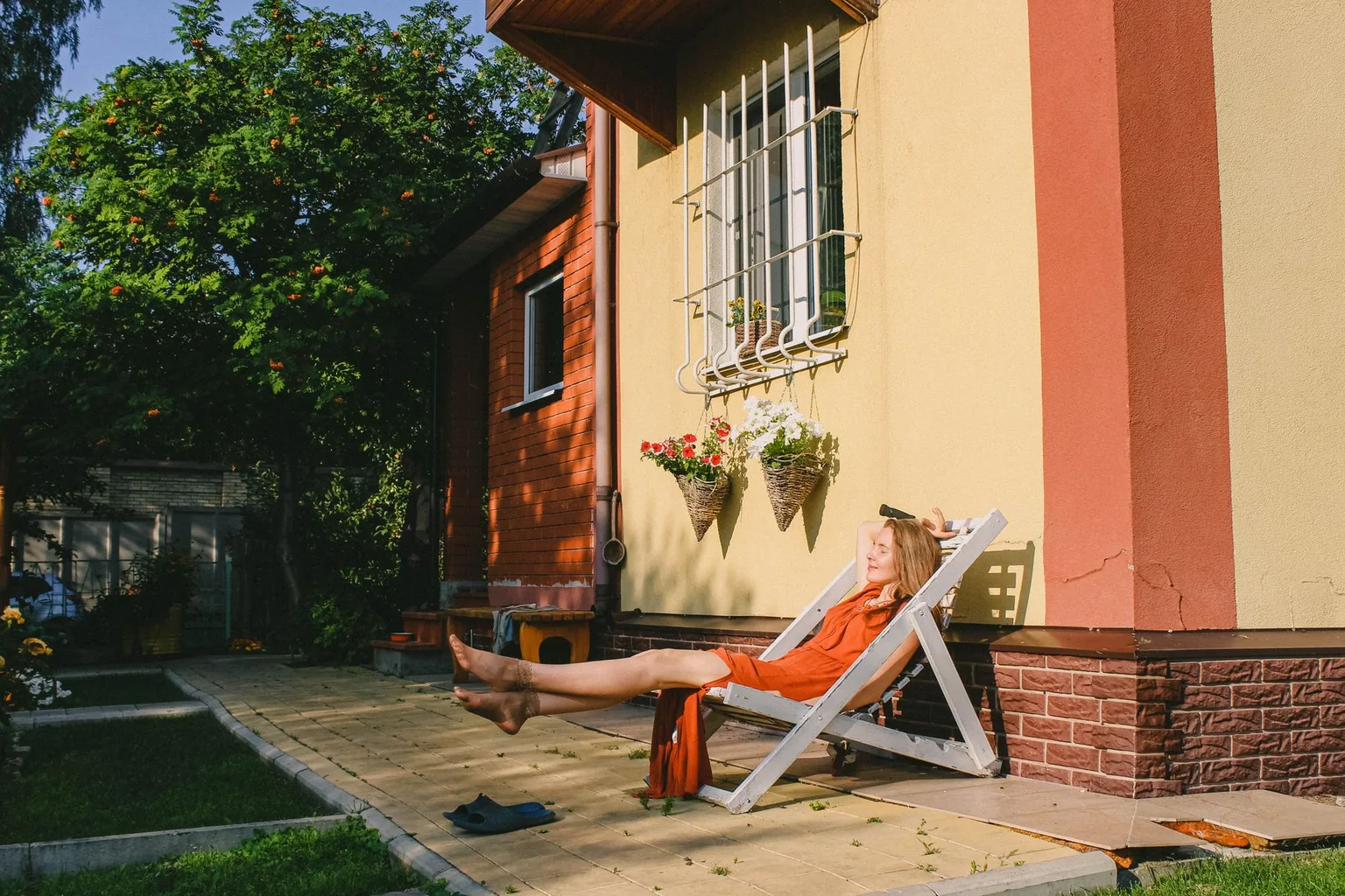 Person reclining on a folding outdoor lounge chair in a garden